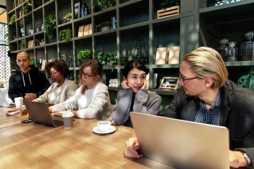 five people sitting near table using laptops inside room